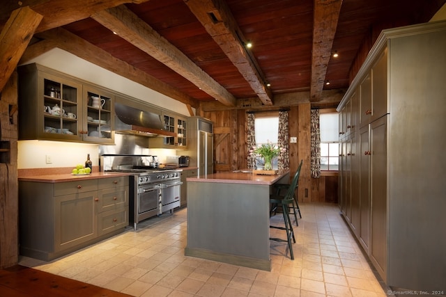 kitchen with double oven range, beam ceiling, wall chimney range hood, wood ceiling, and light tile floors