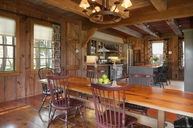 dining area featuring hardwood / wood-style floors, beam ceiling, a chandelier, wooden walls, and wooden ceiling