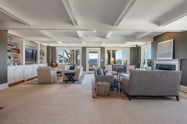 living room with built in features, light colored carpet, and beam ceiling