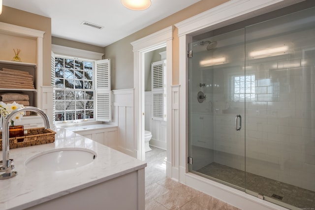 bathroom featuring vanity, walk in shower, tile patterned flooring, and toilet