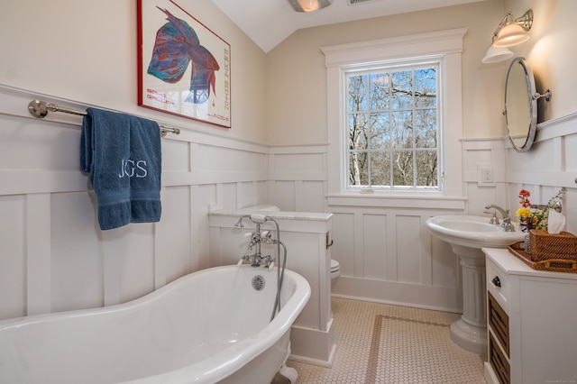 bathroom with vaulted ceiling, a bathing tub, tile patterned flooring, and toilet