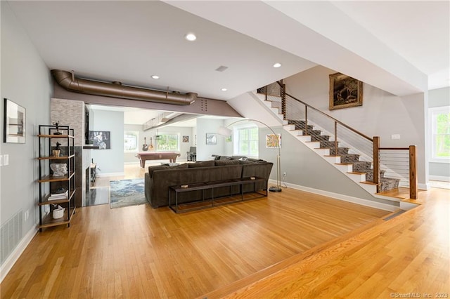 living area with wood finished floors, visible vents, baseboards, recessed lighting, and stairs