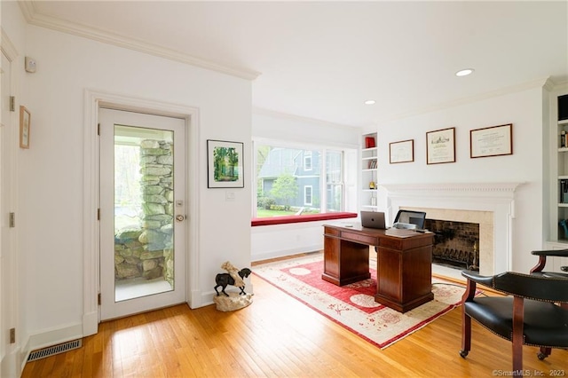 home office with a wealth of natural light, visible vents, light wood finished floors, and crown molding