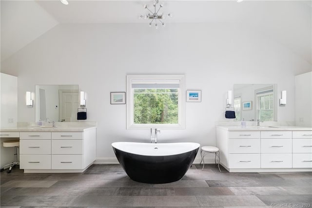 full bathroom with a soaking tub, high vaulted ceiling, two vanities, and a sink