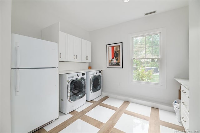 washroom with visible vents, cabinet space, baseboards, and separate washer and dryer