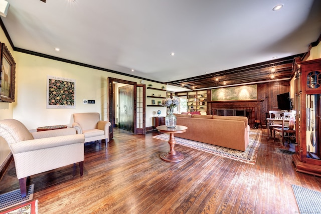 living room featuring a brick fireplace, hardwood / wood-style floors, and crown molding