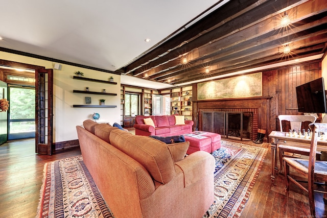 living room featuring ornamental molding, a brick fireplace, wooden walls, and wood-type flooring