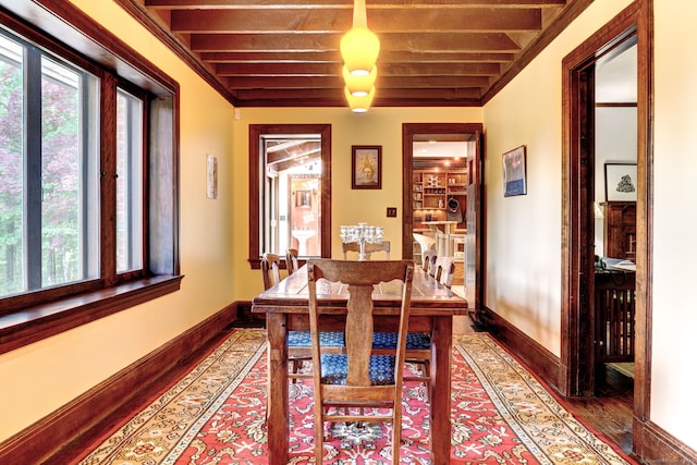 dining room with hardwood / wood-style flooring, crown molding, and beamed ceiling