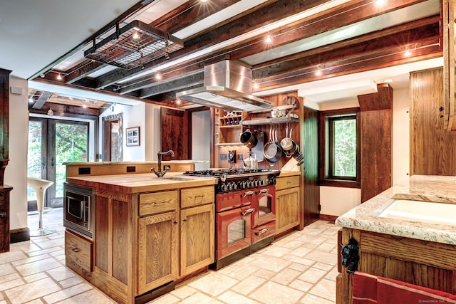 kitchen with sink, an island with sink, island range hood, and stainless steel microwave