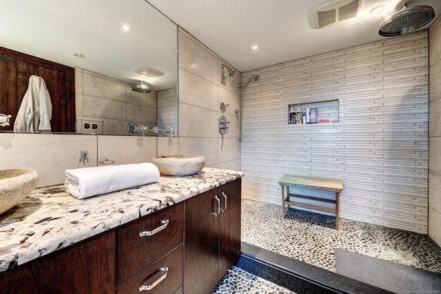 bathroom with a shower, vanity, and tile walls