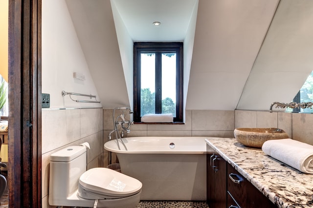 bathroom featuring tile walls, a bathing tub, toilet, and vanity