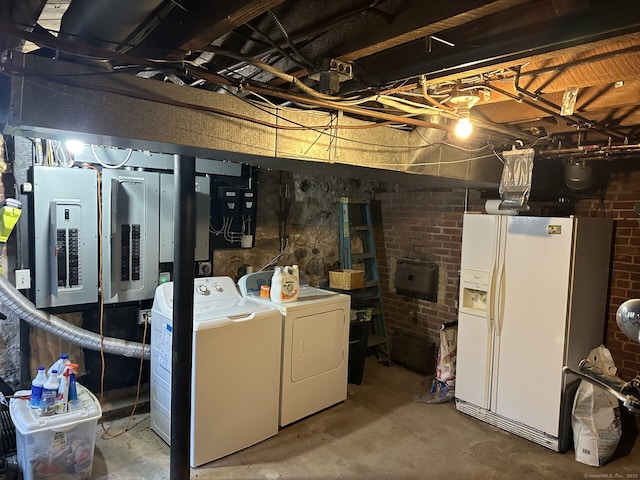 basement with washer and clothes dryer, electric panel, and white fridge with ice dispenser