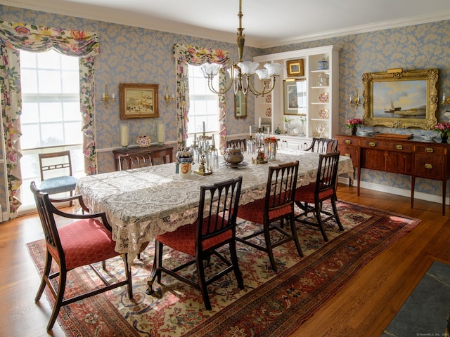 dining space with hardwood / wood-style floors, crown molding, and a chandelier