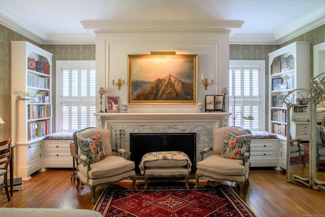 sitting room with hardwood / wood-style flooring, crown molding, and a fireplace