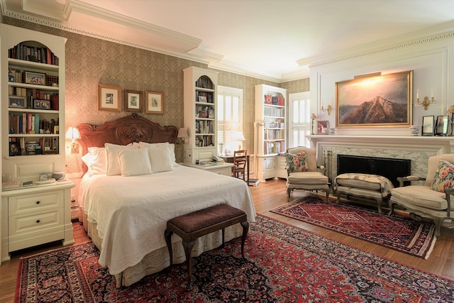 bedroom featuring ornamental molding, wood-type flooring, and a fireplace