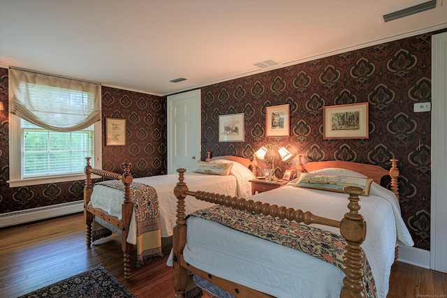 bedroom featuring crown molding, hardwood / wood-style flooring, and baseboard heating