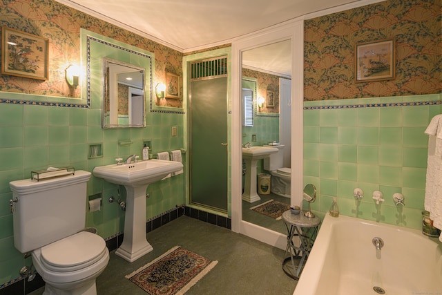 bathroom featuring a tub to relax in, toilet, sink, and tile walls