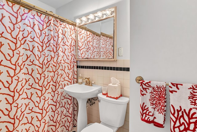 bathroom featuring a shower with curtain, toilet, and tile walls