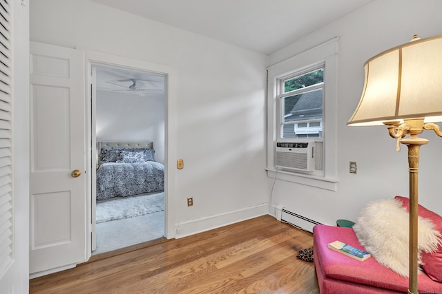 sitting room featuring hardwood / wood-style floors, a baseboard radiator, cooling unit, and ceiling fan