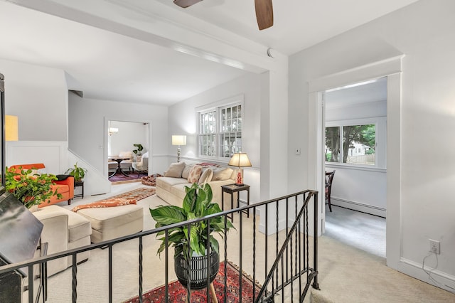 living room with light carpet, a wealth of natural light, baseboard heating, and ceiling fan