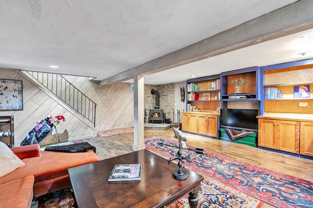 living room featuring a wood stove, wooden walls, and light hardwood / wood-style flooring