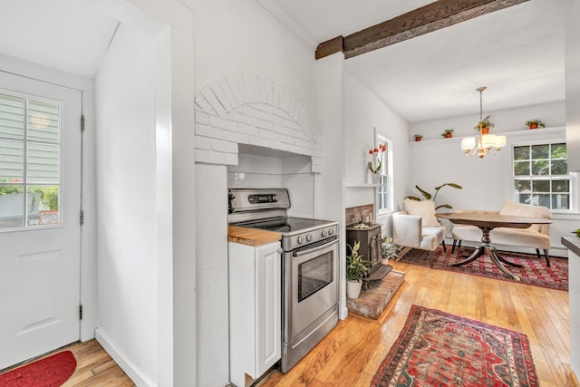 kitchen with a wealth of natural light, light hardwood / wood-style floors, hanging light fixtures, and stainless steel range with electric cooktop