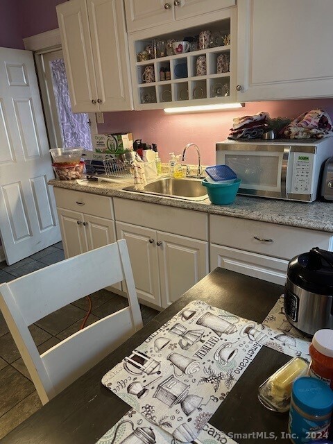 kitchen with white cabinetry, dark tile patterned floors, and sink