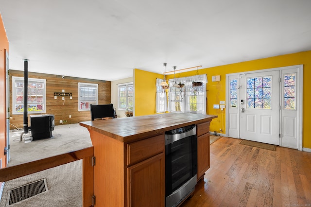 kitchen featuring light hardwood / wood-style flooring, beverage cooler, wood walls, hanging light fixtures, and butcher block countertops