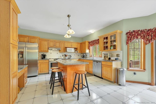 kitchen featuring tasteful backsplash, stainless steel appliances, a center island, hanging light fixtures, and a breakfast bar area