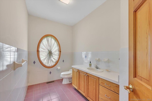 bathroom featuring toilet, vanity, tile patterned floors, and tile walls