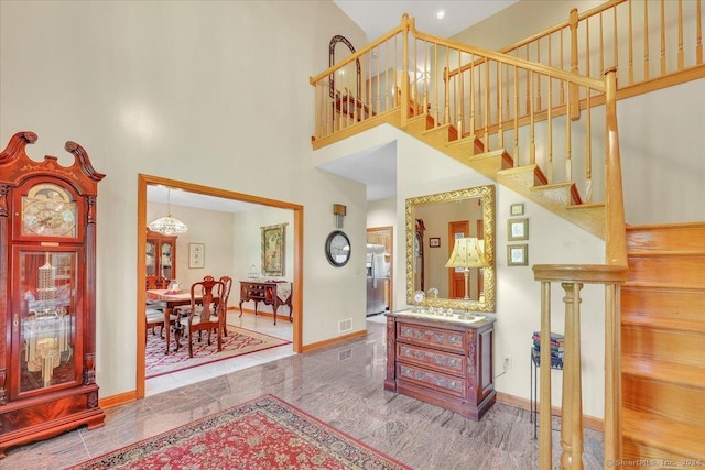 entryway featuring a towering ceiling and a notable chandelier