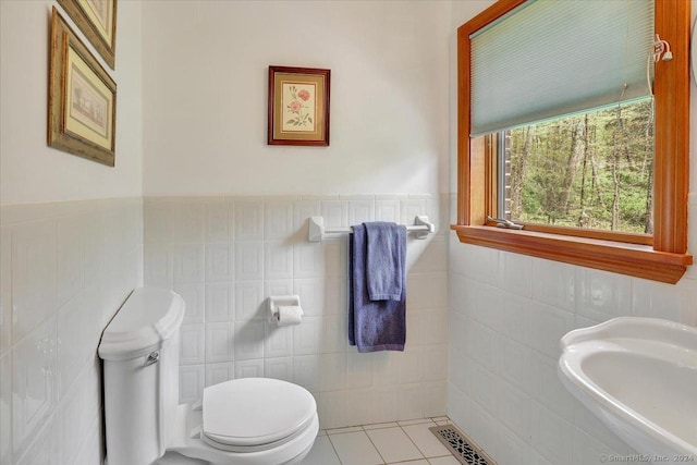 bathroom with tile patterned flooring, toilet, and tile walls