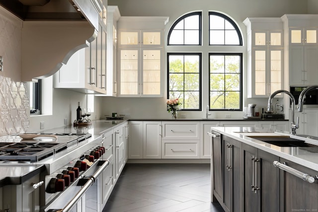 kitchen with white cabinetry, range with two ovens, parquet flooring, sink, and custom exhaust hood