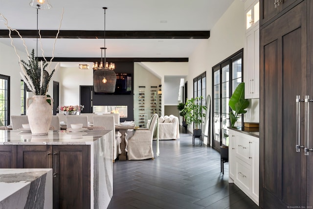 kitchen with dark brown cabinets, dark parquet floors, beamed ceiling, light stone counters, and white cabinets