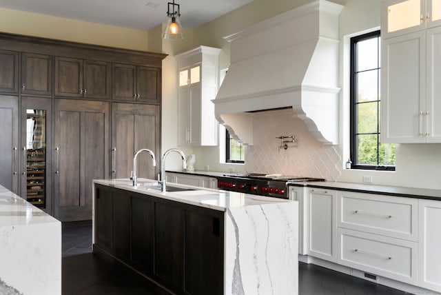 kitchen with white cabinetry, light stone countertops, tasteful backsplash, and custom exhaust hood