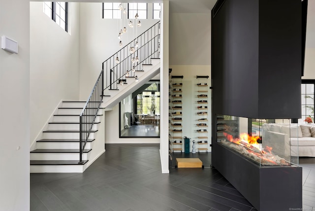 interior space featuring dark parquet floors, a towering ceiling, and a multi sided fireplace