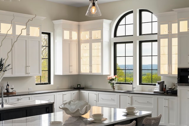 kitchen with pendant lighting, plenty of natural light, oven, and white cabinetry