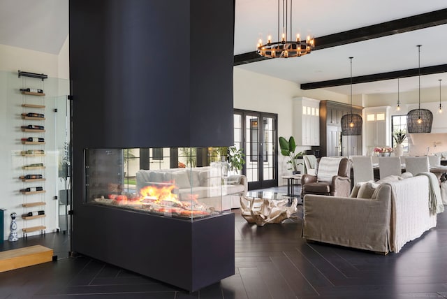 living room featuring dark hardwood / wood-style floors, beamed ceiling, an inviting chandelier, and french doors