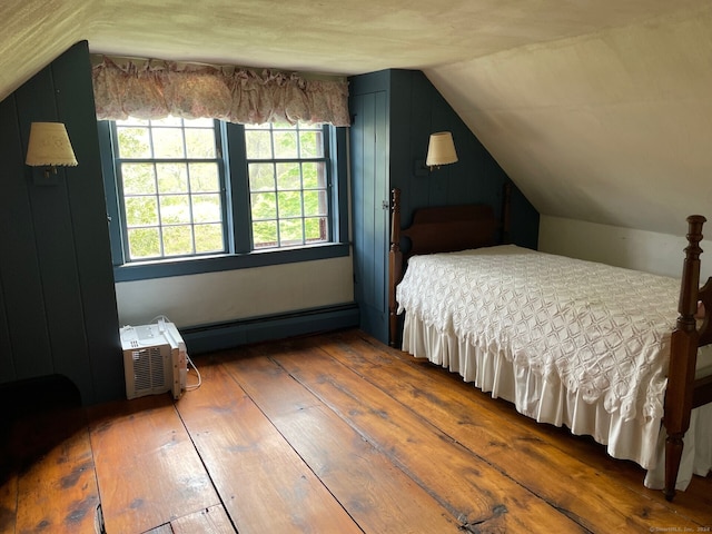 bedroom featuring a baseboard heating unit, dark hardwood / wood-style flooring, a wall mounted AC, and vaulted ceiling