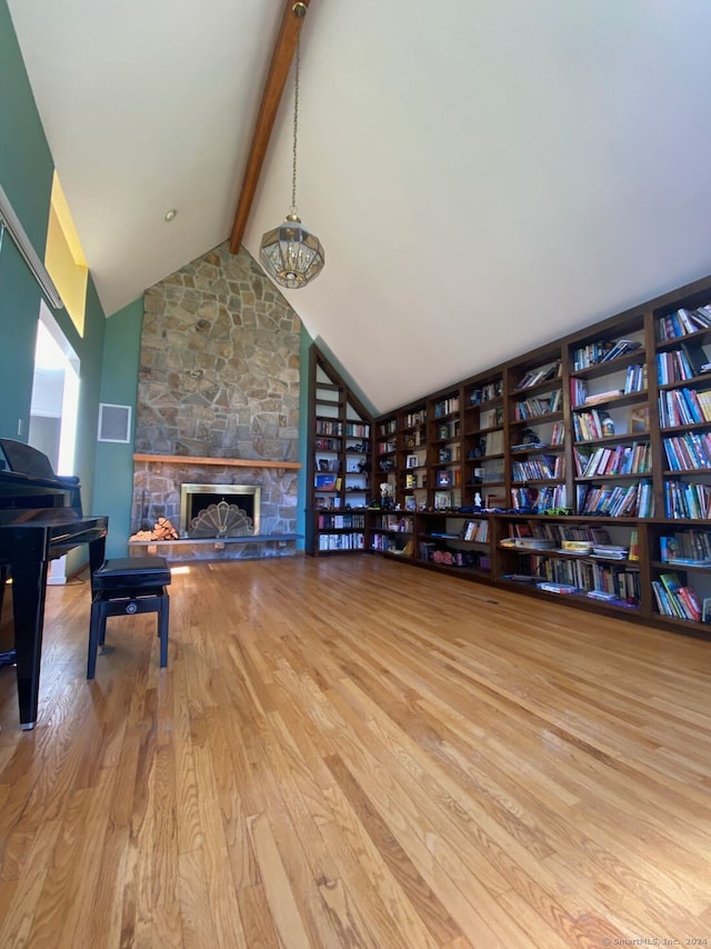 living room featuring high vaulted ceiling, a fireplace, light hardwood / wood-style flooring, an inviting chandelier, and beam ceiling