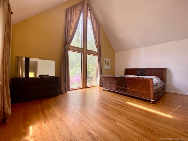 bedroom featuring high vaulted ceiling and hardwood / wood-style flooring