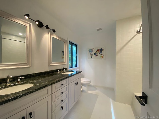 bathroom featuring tile floors, toilet, vanity with extensive cabinet space, and dual sinks