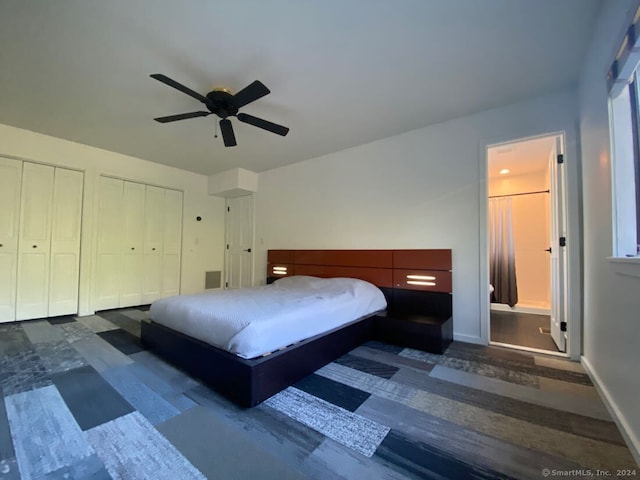 bedroom featuring dark hardwood / wood-style flooring, ceiling fan, ensuite bath, and two closets