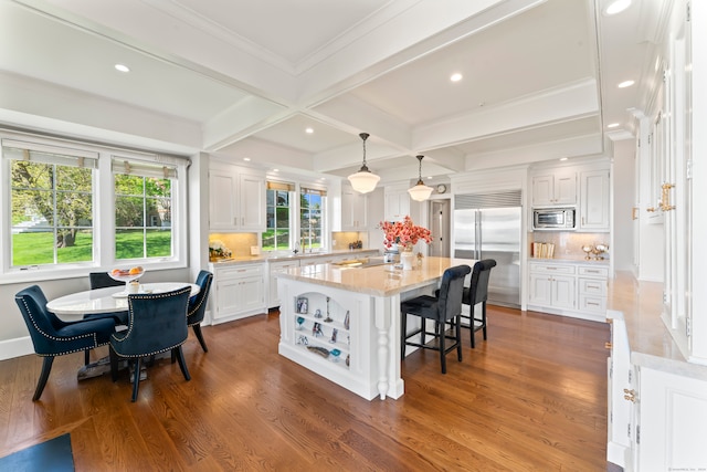 kitchen with backsplash, hanging light fixtures, white cabinetry, and built in appliances