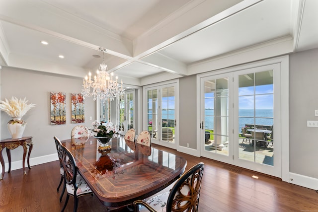 dining space with dark hardwood / wood-style floors, beamed ceiling, an inviting chandelier, and a water view