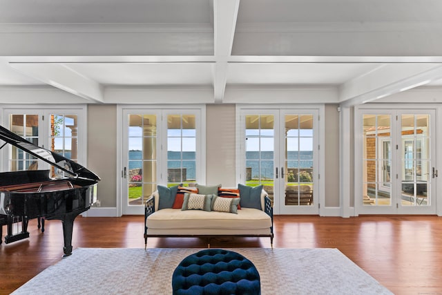 sunroom / solarium featuring plenty of natural light, beam ceiling, french doors, and a water view