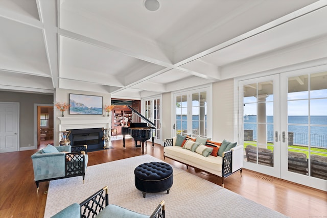 living room with french doors, beamed ceiling, a water view, wood-type flooring, and coffered ceiling