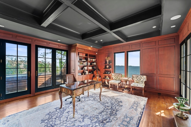 office space featuring hardwood / wood-style flooring, a water view, beam ceiling, a healthy amount of sunlight, and coffered ceiling