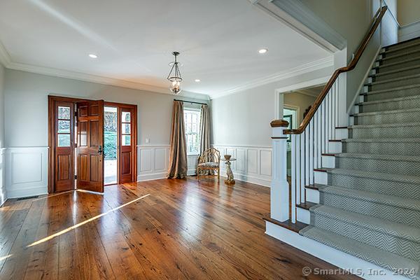 foyer entrance featuring crown molding and dark wood-type flooring