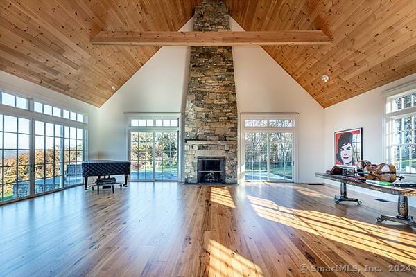 unfurnished living room featuring a fireplace, beamed ceiling, high vaulted ceiling, and hardwood / wood-style floors